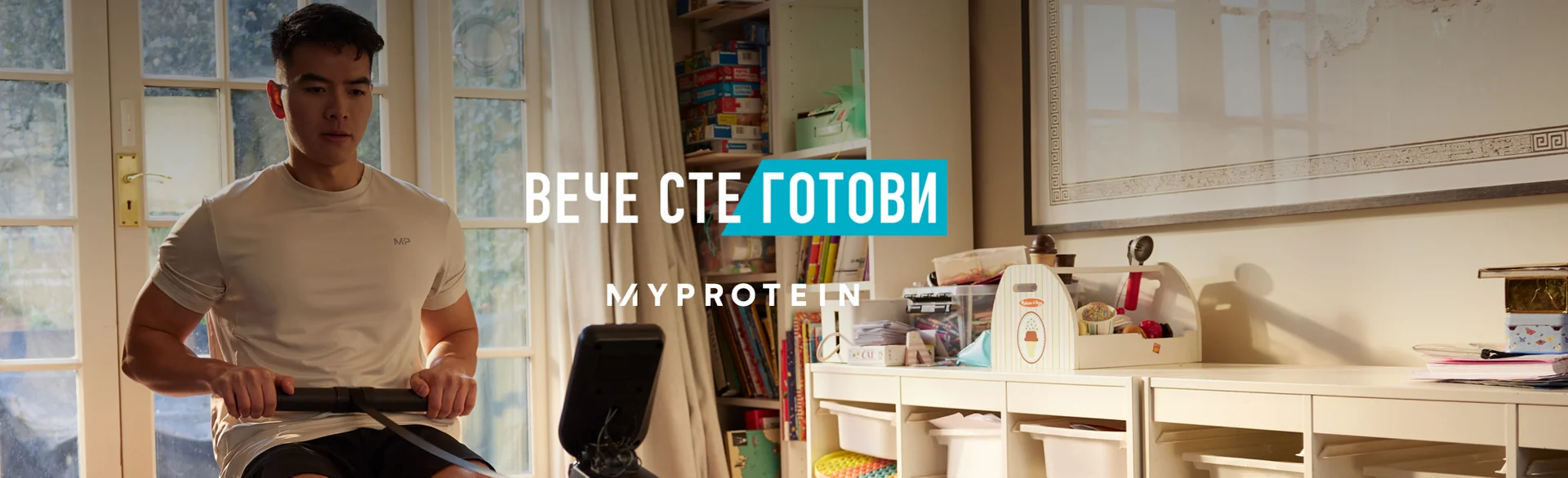A man workout out on a rowing machine at home with the words 'You're Already Ready - MYPROTEIN' overlaying.